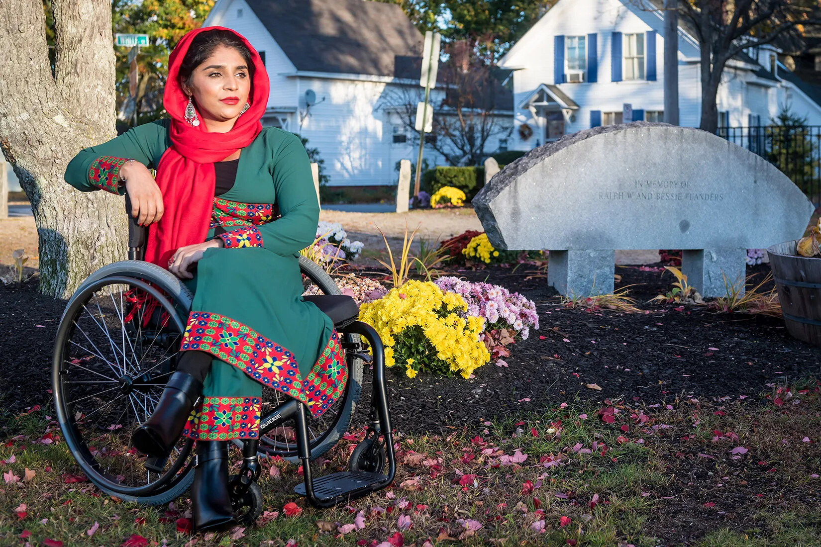 woman is sitting in a wheelchair in front of a stone memorial. 