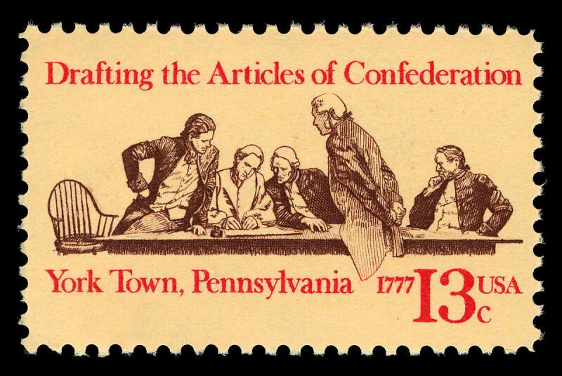 A black and white drawing of five men gathered around a long table, looking at a large document. They all wear collared shirts and vests, long coats, and have their long hair pulled back and tied up with a ribbon behind their head. Two lines of text, typed in red ink, border the drawing. The top line of text reads "Drafting the Articles of Confederation" and the bottom line reads "York Town, Pennsylvania 1777 13c USA."