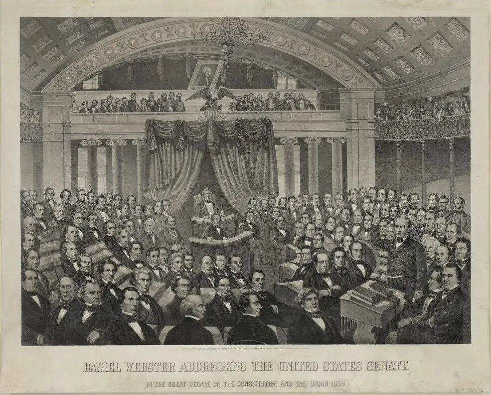 A black and white drawing of a large group of men sitting at desks in a semi-circle. They are all looking at a man with one of his arms raised in the right-hand corner of the drawing. The title of the drawing, located along the bottom border, reads: "DANIEL WEBSTER ADDRESSING THE UNITED STATES SENATE/IN THE GREAT DEBATE ON THE CONSTITUTION AND THE UNION 1850."