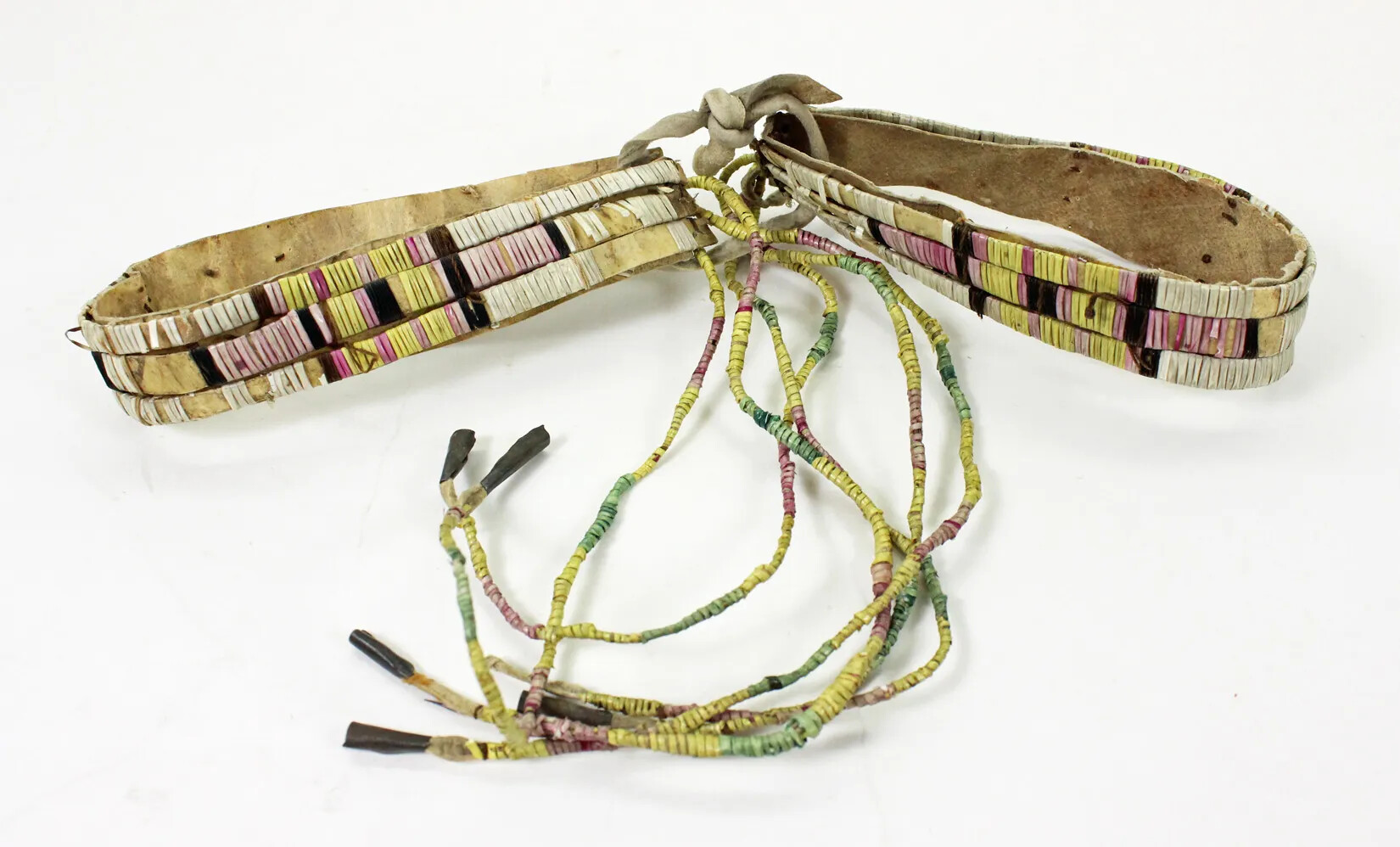 Two leather bracelets attached to one another by strip of leather, and a dangling set of decorated strings of differing colors. The bracelets are decorated with thin, vertical beads of different colors.