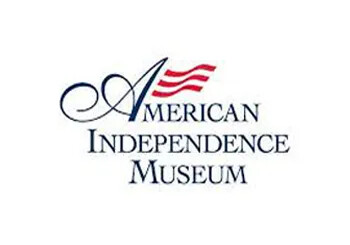 Logo of the American Independence Museum with a red flag graphic.