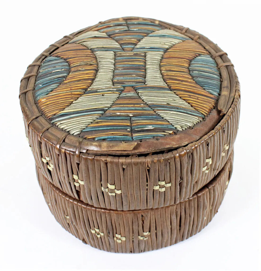 A small circular box with ornate designs on the box's cover and sides. The cover of the box is decorated with in thin colored strips and the sides of the box are decorated in thin brown and white strips.