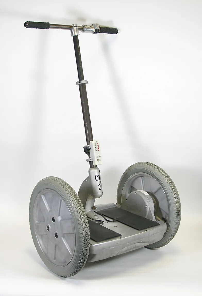 A horizontal base is connected to two large wheels. On top of the base is a vertical bar that connects the base to a set of handle bars.